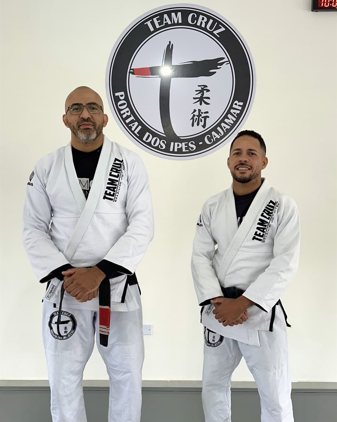 Professores faixa-preta da Team Cruz Cajamar em frente ao logo da unidade — Portal dos Ipês
